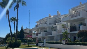 A swimming pool with clear blue water, surrounded by a white building with balconies and palm trees. - Apartment with sea views in a quiet area (Alcorrín)