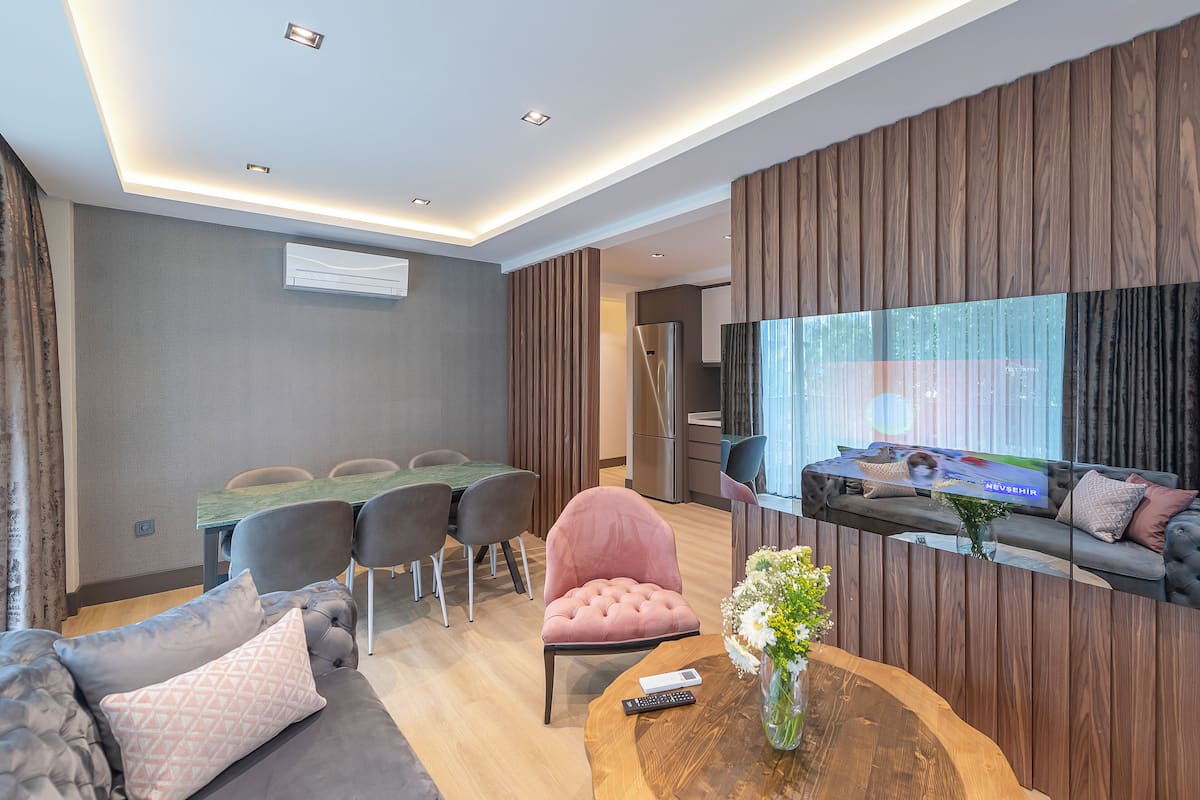 Un salon moderne comprenant un canapé, une table basse, un téléviseur et un coin repas avec des chaises et une table.