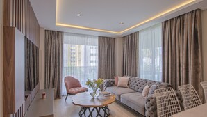 A modern living room with a grey sofa, a pink chair, and a wooden coffee table with a vase.