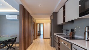 A modern kitchen with built-in appliances, a dining area with a table and chairs, and a wooden partition.