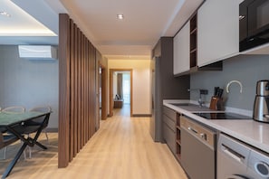 A modern kitchen with built-in appliances, a dining area with a table and chairs, and a wooden partition. - Sealife Royal (Konyaalti)
