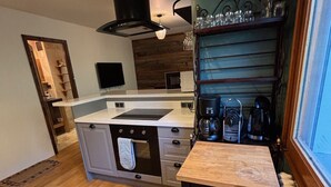Una cocina con una isla central, estufa, horno y cafetera.