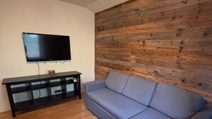 Una sala de estar con un sofá modular, un mueble multimedia negro y una pared de acento de madera.