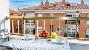 En balkon med et bord dækket til morgenmad, inklusive æbler, et glas juice og bagværk.