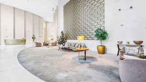 Een ruime lobby met een gebogen zitgedeelte, een receptiebalie en een decoratieve muur met een geometrisch patroon.