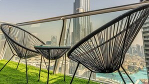 Een balkon met uitzicht op de Burj Khalifa, met moderne stoelen en een glazen tafel.
