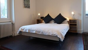 Une chambre à coucher avec un lit, des lampes de chevet, un radiateur et une fenêtre.