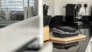Et moderne køkken med en glasbordplade, kaffemaskine og et knivdisplay.
