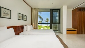 A hotel room with a large bed, a view of the beach, and framed pictures on the wall. - Abogo Resort Villas Beachview Da Nang   (Da Nang)