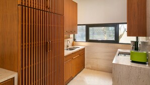 A modern kitchen with wooden cabinets, a sink, and a window. - Abogo Resort Villas Beachview Da Nang   (Da Nang)
