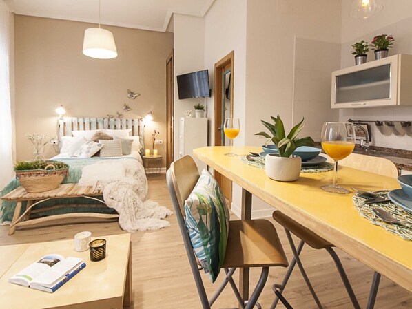 Ein gemütliches Schlafzimmer mit Bett, Nachttisch und Nachttischlampe. Es gibt einen Essbereich mit Tisch, Stühlen und einer Topfpflanze.