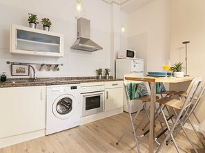 A compact kitchen with a washing machine, microwave, and a small dining area with a table and chairs.