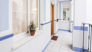 A hallway with white walls, blue trim, and a potted plant on a window sill. - Central Málaga Apartment: Bright, Comfortable, Fully Equipped, Near Attractions (Málaga)