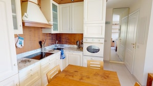 Una cocina compacta con armarios blancos, una mesa de madera y un horno doble.