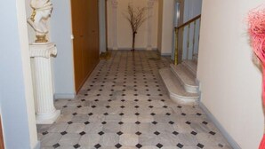 Un pasillo con suelo de baldosas, una estatua a la izquierda y una escalera a la derecha.
