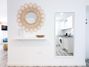 A modern kitchen with white cabinetry, a built-in washing machine, and a decorative wall piece above a shelf with a bowl. - Renovated 2-bedroom apartment, air conditioning, Wi-Fi, Málaga center (Málaga)