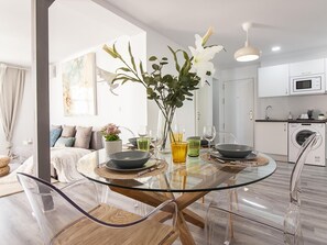 A modern dining area with a glass table, clear chairs, and a vase with flowers. - Renovated 2-bedroom apartment, air conditioning, Wi-Fi, Málaga center (Málaga)