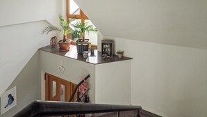 Eine Treppe mit Handlauf, ein kleines Regal mit Topfpflanzen, ein gerahmtes Bild und eine herzförmige Dekoration an der Wand.
