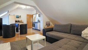 Eine moderne Lofts-Wohnung mit Loft-Küche, einem grauen Ecksofa und einem kleinen weißen Tisch.