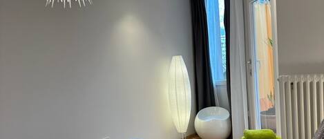 A modern bedroom with a large bed, a unique ceiling light, and a view of the outdoors.