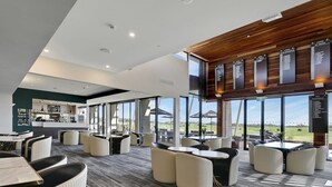A modern indoor space with seating areas, a bar, and large windows offering a view of the outdoors. - Moonah Retreat - 4pm check out Sundays* (Fingal)