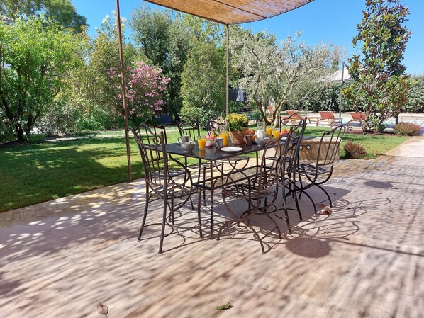 An outdoor patio with a table and chairs, surrounded by greenery and a pool area.