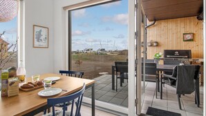 Un comedor con mesa lista para dos, vistas al exterior y una parrilla.