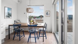 Una cocina moderna con una mesa de madera, sillas azules y un ventanal con vistas al exterior.