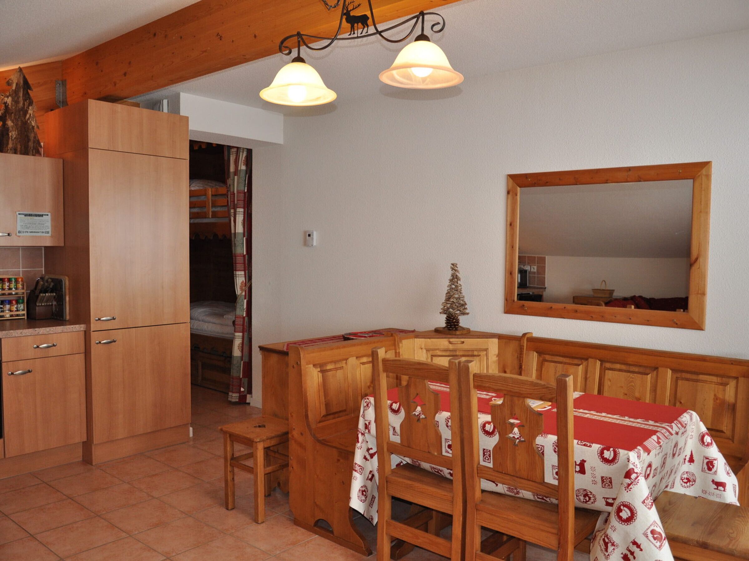 A cozy dining area with wooden furniture, a table with a festive tablecloth, and a mirror on the wall.