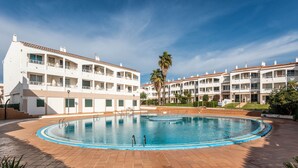 A hotel with a swimming pool, multiple balconies, and a palm tree. - UDANE (Cala´n Blanes)