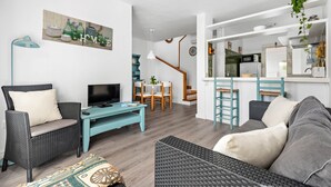 A modern living room with a sofa, a TV, and a dining area with chairs and a table. - UDANE (Cala´n Blanes)