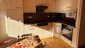Une cuisine avec des meubles de rangement en bois, un four à micro-ondes, une cuisinière et un coin repas comprenant une table et des chaises.