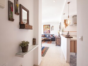 A modern interior with a hallway leading to a living area, featuring a glass shelf with a plant, a mirror, and decorative items. - Bright apartment in Malaga center, 2 bedrooms, newly renovated (Málaga)