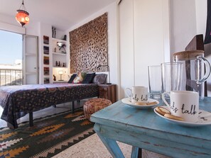 A bedroom with a bed, a nightstand, a decorative wall, a window, and a table with a mug and glasses. - Bright apartment in Malaga center, 2 bedrooms, newly renovated (Málaga)