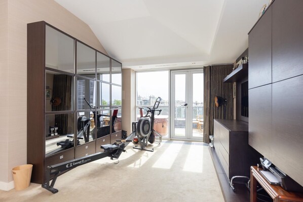 A modern apartment with a large mirror, exercise equipment, and a balcony with a city view. - Beautiful Penthouse with Terrace & Jacuzzi (Edinburgh)