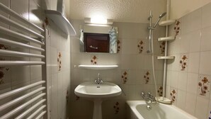 Ein Badezimmer mit einem weißen Waschbecken, einer Badewanne, einer Dusche und einem Handtuchhalter.