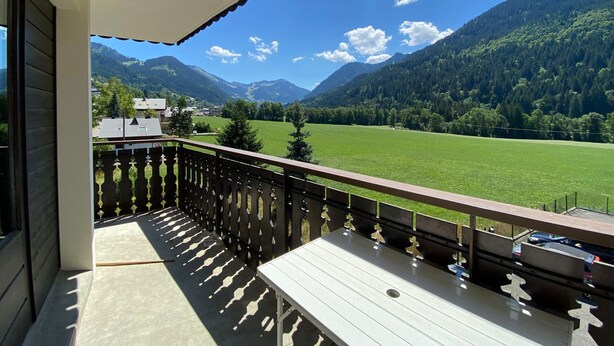 Ein Balkon mit Blick auf ein grünes Feld und Berge.