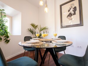Un coin repas avec une table ronde en verre, des chaises noires et un tableau encadré accroché au mur.