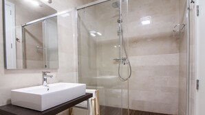 Une salle de bain moderne avec un lavabo blanc, une douche en verre et un plancher en bois.