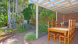 A covered outdoor dining area with a brick wall and a pergola.