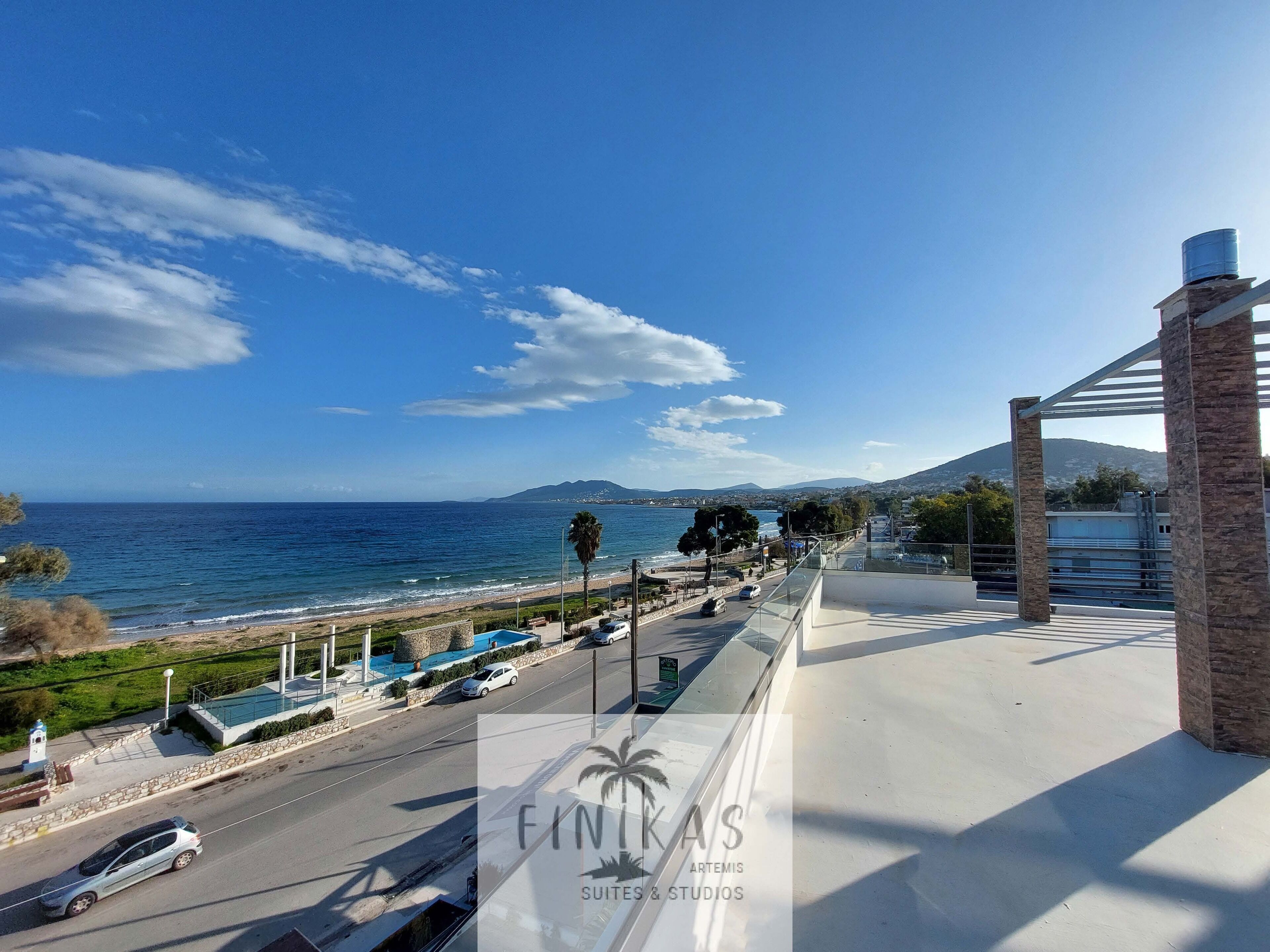 A coastal view with a road, a beach, and a mountain in the distance.