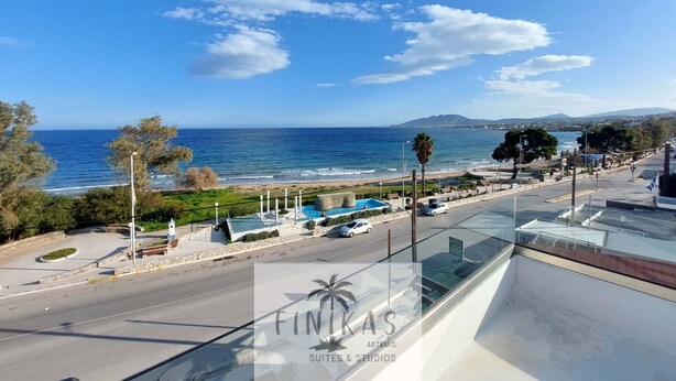 A coastal view with a clear sky, a road, and a parking area. - Finikas Suites & Apartments Airport (Spata-Artemida)