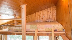 Eine Holzhütte mit Etagenbett, Holzwänden und einem Fenster.