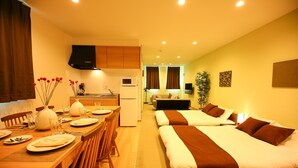 A hotel room with a kitchenette, a dining area, and a bed with a brown headboard. - PrimeRoomBeppu Hamawakionsenmae (Beppu)