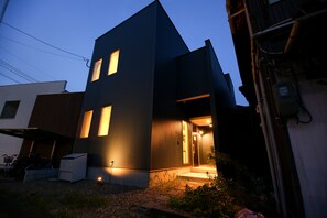 Un bâtiment moderne à deux étages, doté d’une façade sombre et de fenêtres illuminées.