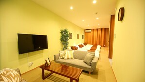 A living room with a flat-screen TV, a sofa, a coffee table, and a plant. - PrimeRoomBeppu Hamawakionsenmae (Beppu)