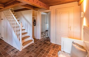 Stairs lead to an upper level, with a door, radiator, and light switch.