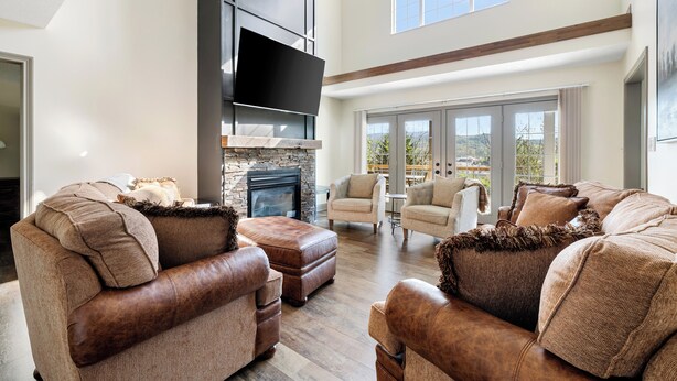 A spacious living room with leather sofas, a fireplace, and large windows offering a view.