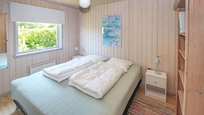 A bedroom with two beds, a window, a radiator, a painting, and a nightstand with a lamp. - 2 bedroom beautiful home in Samsø (Samsø)