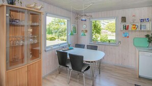 A dining area with a round table and four chairs, a wooden cabinet with glass doors, and a view of greenery outside. - 2 bedroom beautiful home in Samsø (Samsø)